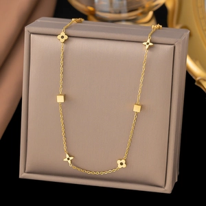 Goldene Titanstahl-Halskette mit hohlen Kleeblättern und geometrischen Würfeln auf Schmuckbox
