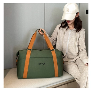 Detail of dark green fitness bag with orange straps and black lettering for travel