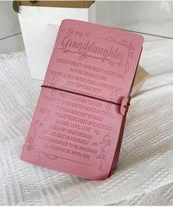 Close-up of pink leather notebook with brown elastic strap and antique metal charms