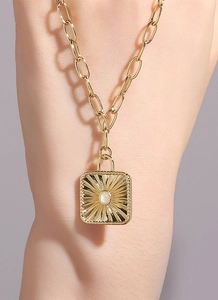 Detail view of gold sunburst pendant with white opal inlay on textured chunky chain