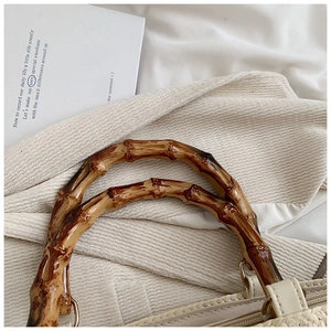 Detailed macro view of the natural bamboo handles on a woven beige summer tote bag