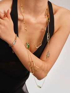 Detail of layered gold necklaces with colorful oval gemstones on a black dress