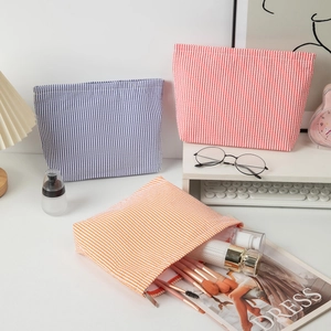Detailed scene of seersucker toiletry bags in blue, red, and orange stripes on desk