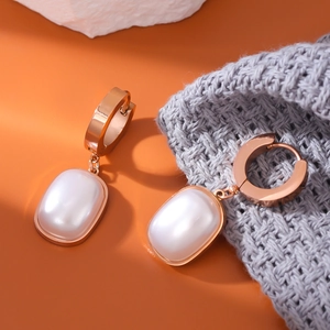 Elegant rose gold square pearl drop earrings with oval pendant on orange background