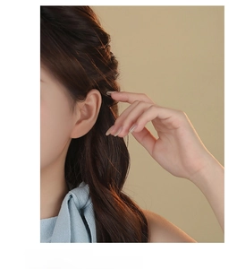 Close-up of golden flower stud earring with five-petal design on earlobe