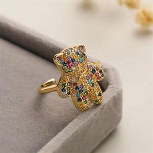 Macro shot of gold-plated bear ring set with colorful zircons on grey velvet background