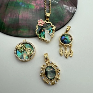 Detail of 18K gold shell pendants featuring cat, koi fish, and dreamcatcher designs