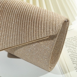Detalle de cerca de la tela con purpurina oro champán y textura plisada del bolso de noche