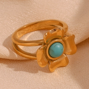 Detail of 18K gold plated flower ring with a turquoise stone inlay on a fabric base