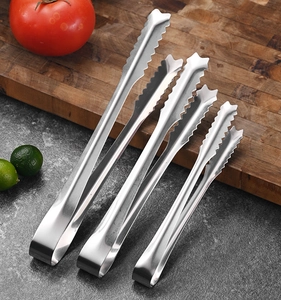 Detail of three mini stainless steel food tongs with star-shaped serrated heads on marble
