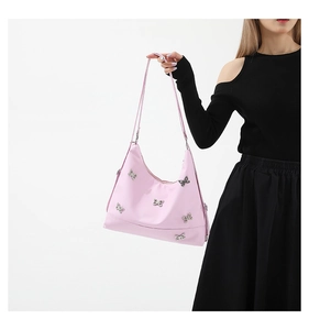 Detailed view of pink nylon shoulder bag with decorative silver butterfly metal buckles