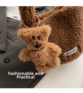 Close-up of a brown plush bear charm attached to a fluffy bucket bag with logo tag