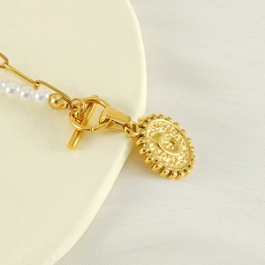 Macro shot of gold OT toggle clasp with pearl chain and letter C coin pendant necklace