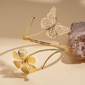 Detail of gold spiral arm cuff featuring hollow butterfly and rhinestone flower decoration