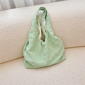 Detail of light green seersucker tote bag with textured striped fabric on beige sofa