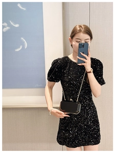 Mirror selfie showing a black geometric acrylic clutch bag with a gold chain strap