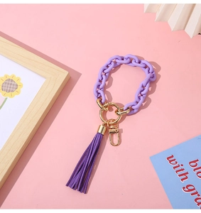 Detail of purple acrylic chain bracelet keychain with gold ring and soft suede tassel