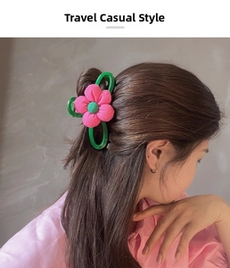 Détail d'une grande pince à cheveux fleur rose en tissu sur un modèle au style élégant