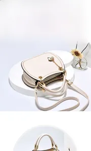 Close-up of warm beige handbag featuring golden round handles and leaf charms