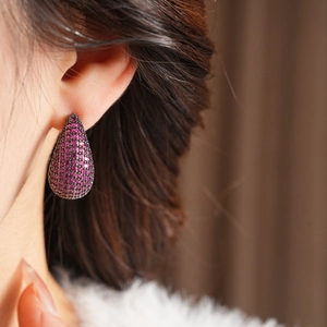 Macro detail of vintage teardrop earrings featuring ruby red pave-set stones on dark metal