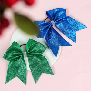 Close-up of glitter hair bows with rhinestones in blue and green on a white plate