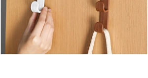 Close-up of adhesive door hooks in white and brown plastic holding a woven bag