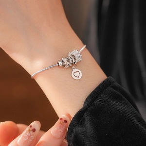 Close-up of 925 silver snake chain bracelet featuring heart charms and zircon stones