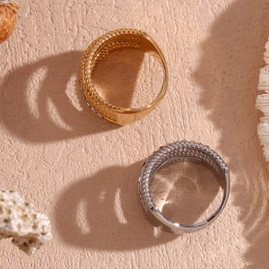 Detail of gold and silver braided rings on a sea-themed background with coral accents