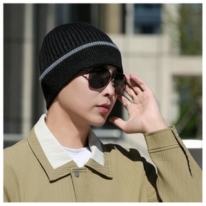 Outdoor shot showing the fit of a black and gray striped ribbed knit winter beanie hat