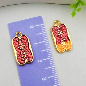 Macro view of Chinese sand gold charms with red and orange enamel lucky locks for jewelry