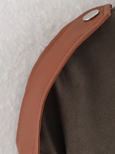 Detail of brown suede fabric, metallic silver button, and white faux fur lining texture