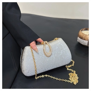 Close-up of silver sequin evening bag with gold diamond buckle and metal chain strap