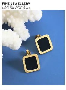 Macro detail of rectangle gold earrings with black inlay and Roman numeral engravings