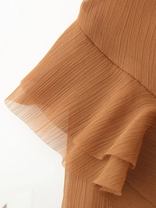 Détail de la robe en mousseline plissée marron avec des volants délicats superposés