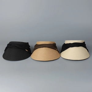 Detailed view of woven straw sun visors in black, khaki, and cream with fabric bows