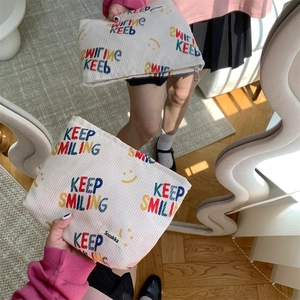 Close-up of cream corduroy makeup bag featuring Keep Smiling text and smiley face design