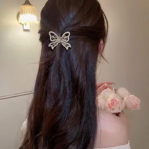Elegant gold butterfly hair claw with pearls on dark hair against vintage rose background