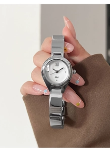 Detail of silver bangle watch with white Roman dial worn on wrist with brown sleeve