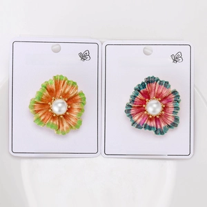 Detailed view of floral brooches with pearl centers and glitter finish on display cards