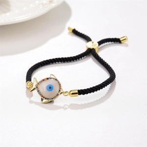 Close-up of golden fish pendant with evil eye and multicolor zircon on black rope