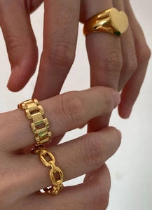 Close-up of golden heart signet, watchband and cuban chain rings worn on fingers