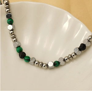Dettaglio macro di bracciale con perle di turchese, lava e acciaio su una conchiglia
