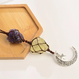 Detail of natural amethyst and quartz raw stones with moon and star metal pendants