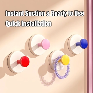 Set of four colorful suction cup hooks in red pink yellow and blue on a bathroom wall