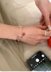 Detail shot of a sweet strawberry charm bracelet with clear glass beads on a model hand
