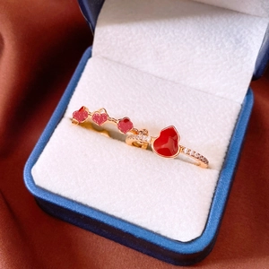 Détail macro des bagues gourde rouge et cœur plaquées or 18 carats dans un écrin bleu