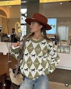 Detail of green and white argyle knit sweater with horse jacquard pattern in a cafe
