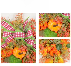 Detail of autumn wreath featuring orange pumpkin, plaid bow, and red berries