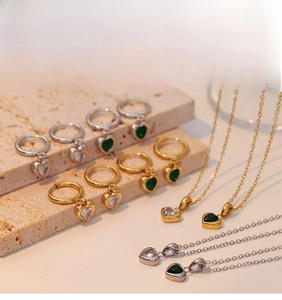 Detail of heart-shaped emerald necklace and earrings set on a natural stone base