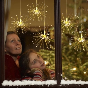 Warm white LED firework lights hanging by a window with a cozy Christmas scene
